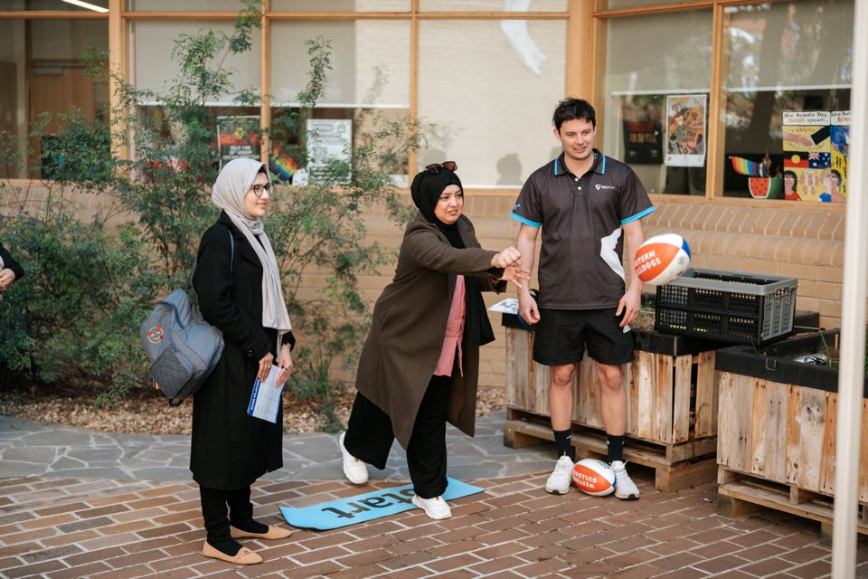 A visitor throws a Western Bulldogs football at a VU Sport activity in the courtyard.
