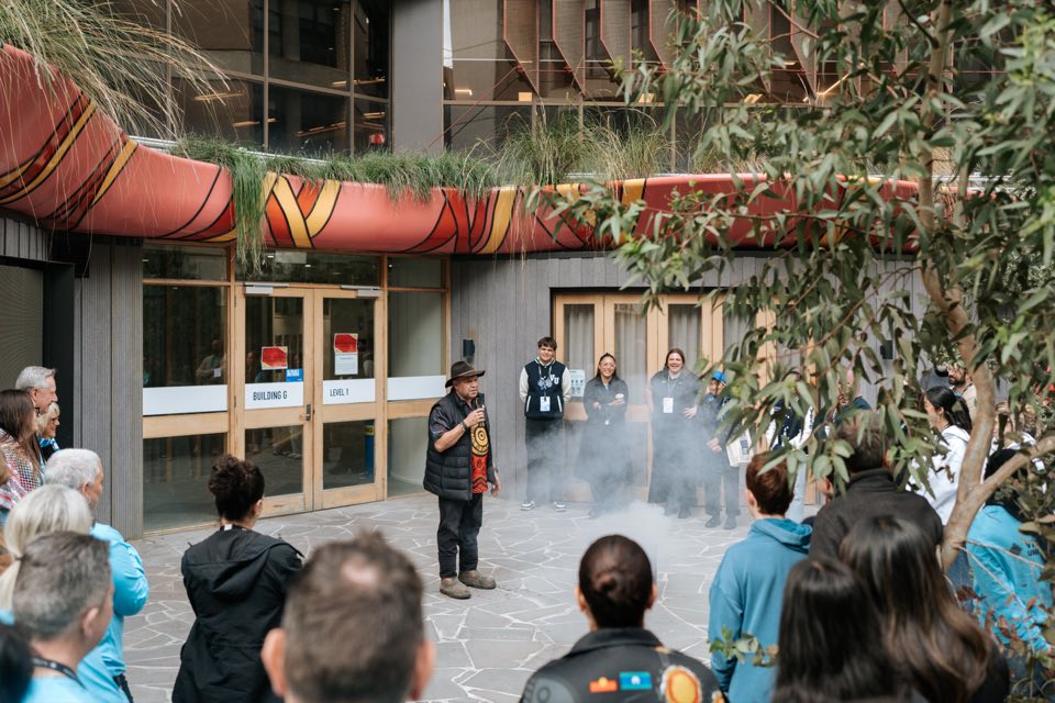 A crowd gathers in the Footscray Park courtyard for a Welcome to Country smoking ceremony.